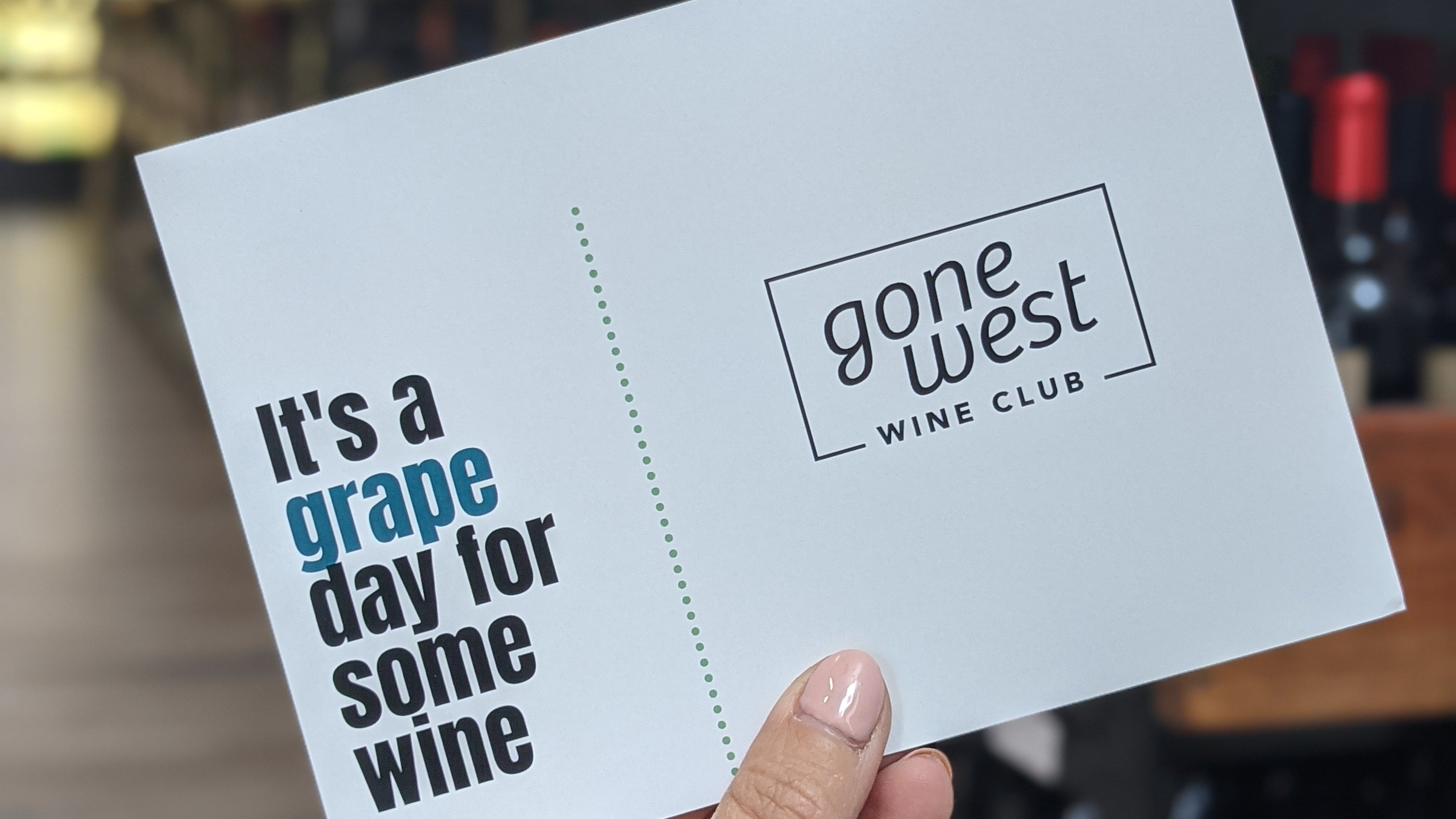 Gone West Wine Club tastig note card held in front of a blurred bar setting